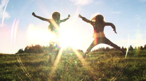 Two girls having fun jumping in the sunset Stock Footage 53752535
