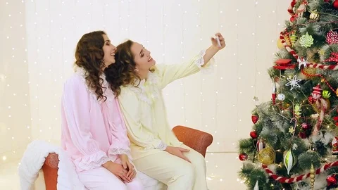 Two girls having fun in their pajamas near the Christmas tree Video stock 70046340