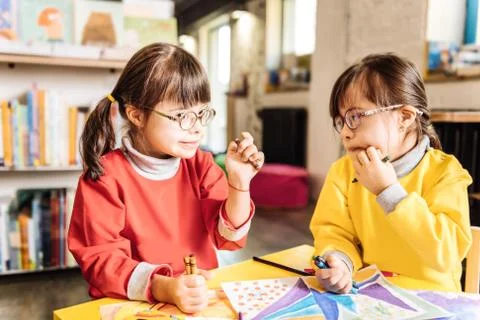 Two girls having light Down syndrome looking at each other Stock Photos