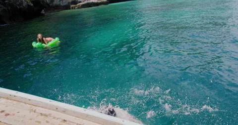 Two girls jumping off authentic long tail boat into clear blue ocean water in Th Stock Footage 201094581