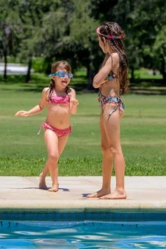 Two girls laugh by a poolside Stock Photos