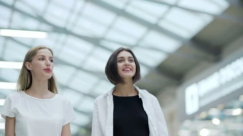 Two girls laughing while walking in shopping mall Stock Footage 97998963