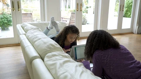 Two girls laying on sofa using their laptops. Stock-Footage 88161512