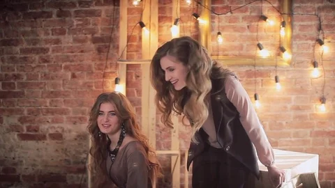 Two girls in the loft interior. Brick wall. Lamps, wooden frames and cubes 動画素材 73242156