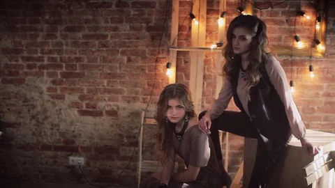 Two girls in the loft interior. Brick wall. Lamps, wooden frames and cubes 库存影片 73242171
