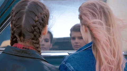 Two girls look at their reflection in the retro car window Stock Footage 88989916