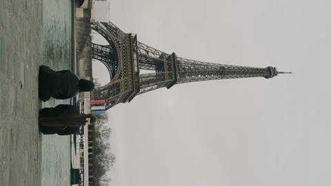 Two girls looking at the Eiffel Tower. Travelers sitting on the embankment in Stock Footage 287605600