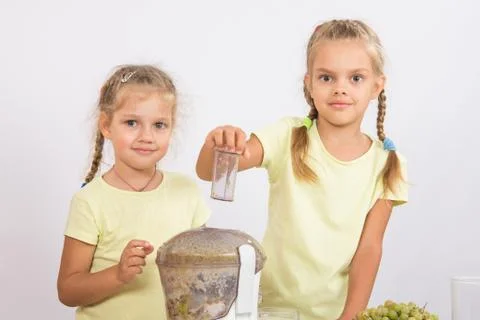 Two girls looking to frame squeezing fruit juice in a juicer Stock Photos