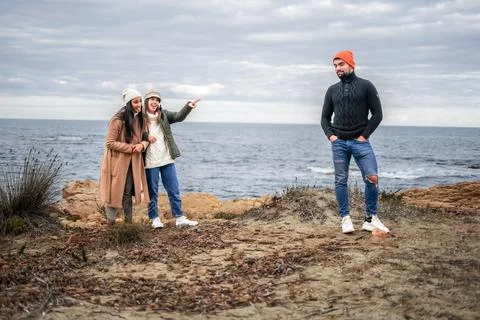 Two girls make fun of a guy outdoors by pointing that he has an amused expres Stock Photos