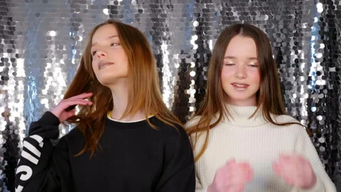 Two girls with makeup posing for the camera, straighten hair with hands, smile Stock Footage 132972097