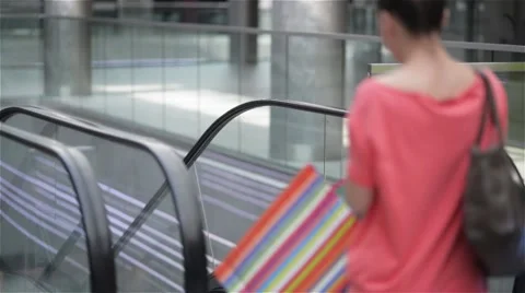Two girls moving down the stairs on escalator in shopping mall, friends are Stock Footage 65833662