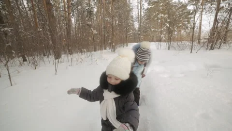 Two girls play in the winter Park, the sisters have fun on a winter day, catch Stock Footage 106960368