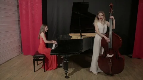 Two girls playing musical instruments. Piano and doublebass Stock Footage 76101123
