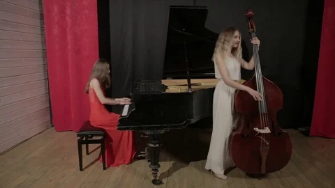 Two girls playing musical instruments. Piano and doublebass Stock Footage 76101307