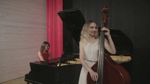 Two girls playing musical instruments. Piano and doublebass Stock Footage 76101441