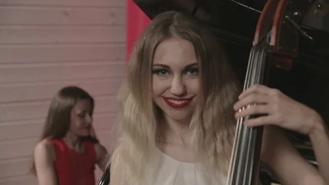 Two girls playing musical instruments. Piano and doublebass Stock Footage 76105850