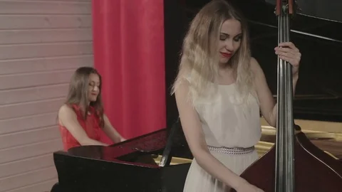 Two girls playing musical instruments. Piano and doublebass Stock Footage