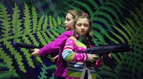 Two girls pose together with machine guns near wall Stock Footage 64210202