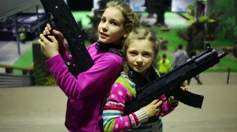 Two girls pose together with machine guns near stairs Stock Footage 64210208
