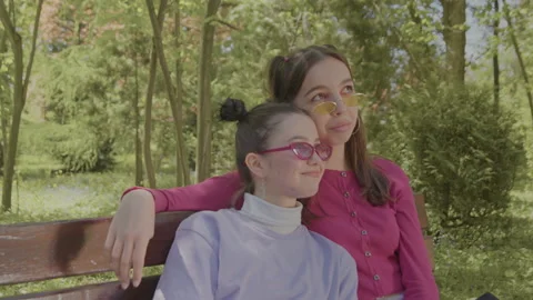 Two girls resting in the park on a bench. Girls who enjoy the moment here and Stock Footage 201699200