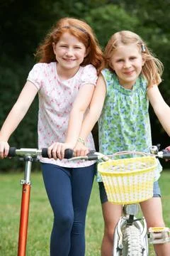 Two Girls Riding Bike And Scooter Together Stock Photos