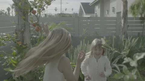 Two girls run through back yard throwing flower petals Stock Footage 68355626