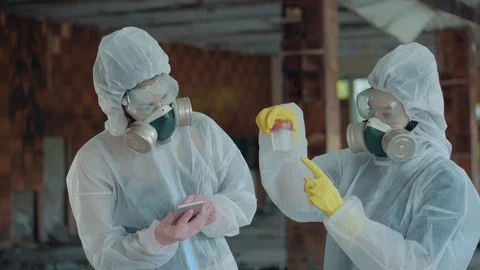 Two girls scientists in a white protective suit and respirator enter the data Stock Footage 111449382