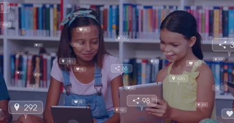 Two girls sharing tablets in school, tapping screens and causing animated Stockbeeldmateriaal 330443816