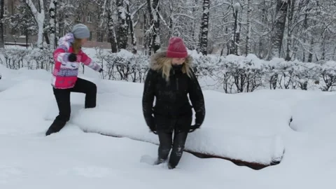 Two girls sit on a bench in the snow 動画素材 85486773