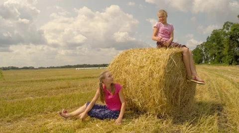 Two girls sit near a stack of straw and talking. Stock Footage 52461036
