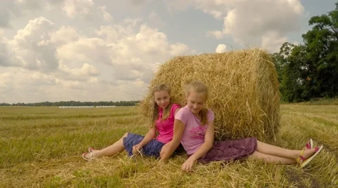 Two girls sit near a stack of straw and talking. Stock Footage 52461375