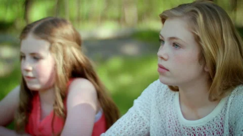 Two Girls Sit Side By Side At Picnic Table, Day Dreaming Video stock 42475688