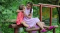 Two girls sits on a wooden bench and embrace HD Footage