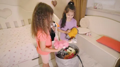 Two girls sorting and organizing stuffed toys in a bright bedroom during Stock Footage 317655871