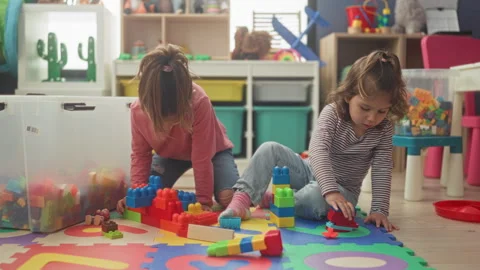 Two girls stacking colorful plastic blocks with hands on a foam playmat ins.. Stock Footage 339137424