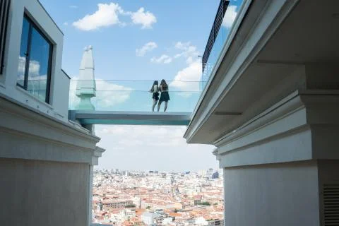 Two girls standing on an elevated platform of a hotel overlooking the city. Stock Photos