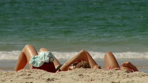 Two girls sunbathing at the beach Stock Footage 20506839