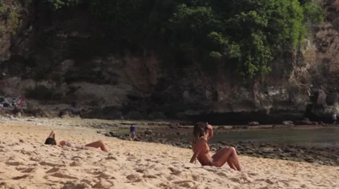 Two Girls Sunbathing on a Sandy Beach Stock Footage 67528864