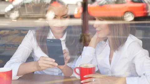 Two girls talking and looking in smartphone Stock Footage 95593298