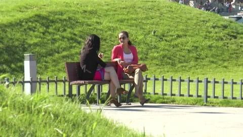 Two girls talking sitting on a bench in a park on a street in Ulaanbaatar. Stock Footage 303510332