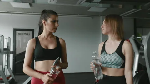 Two girls using smartphone while relaxing after training Stock Footage 133711980