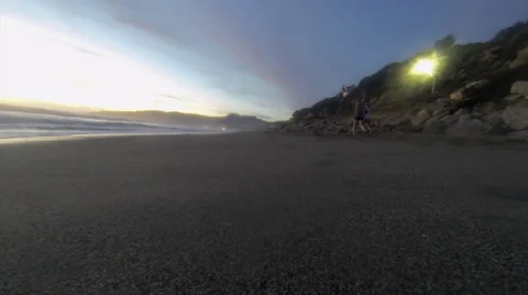 Two girls walk down the vanishing point on the beach at dusk. Vídeo Stock 36128705