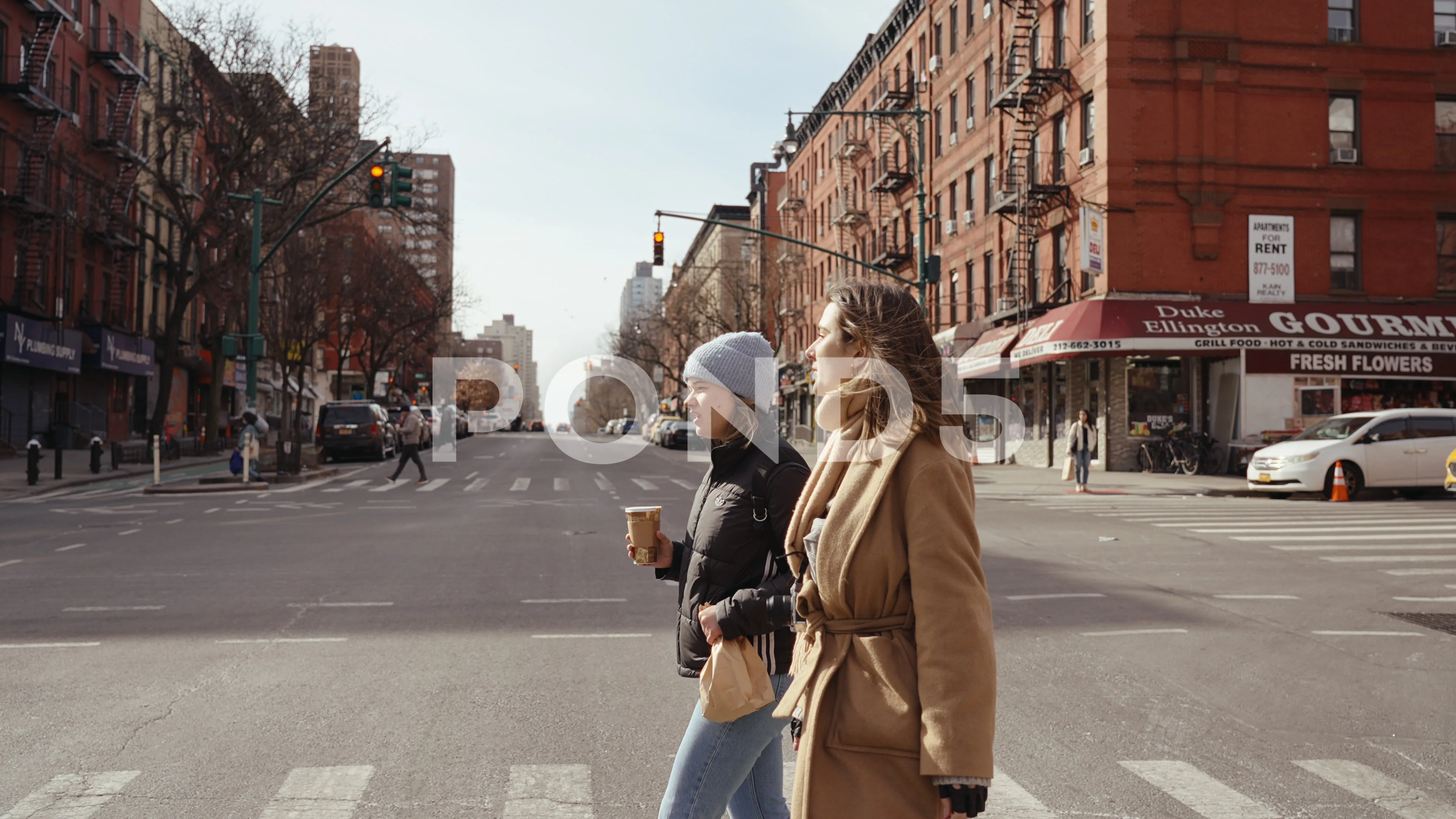 Two girls walking in the streets of New York, drinking coffee talking