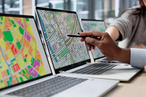 Two GIS Analysts Using Computers In Urban Office, Reviewing Cadastral Maps Fo Foto stock