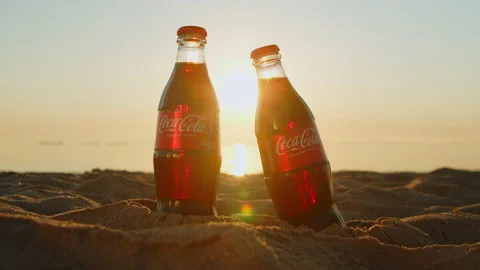 Two glass bottles with coca cola on the beach at sunrise. Stock Footage 216825444