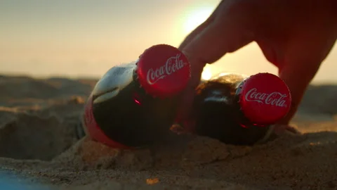 Two glass bottles with Coca Colo lie on the sandy beach close-up. Stock Footage 205571152