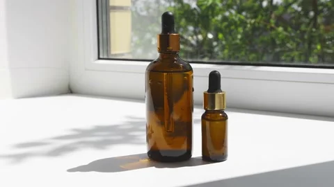 Two glass brown bottles with essential oil, serum on the windowsill front view Stock Footage 196315344