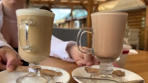 Two glass cups on table with hot drinks cocoa and latte comparison of color and Stock Footage 255973929