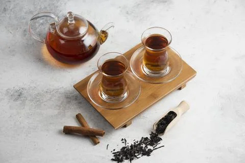 Two glass cups of tea with cinnamon sticks and loose teas Stock Photos