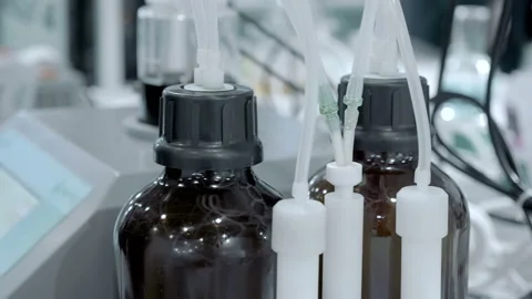 Two glass dark bottles from which a ingredients are fed into a mixing container Stock Footage 187451375